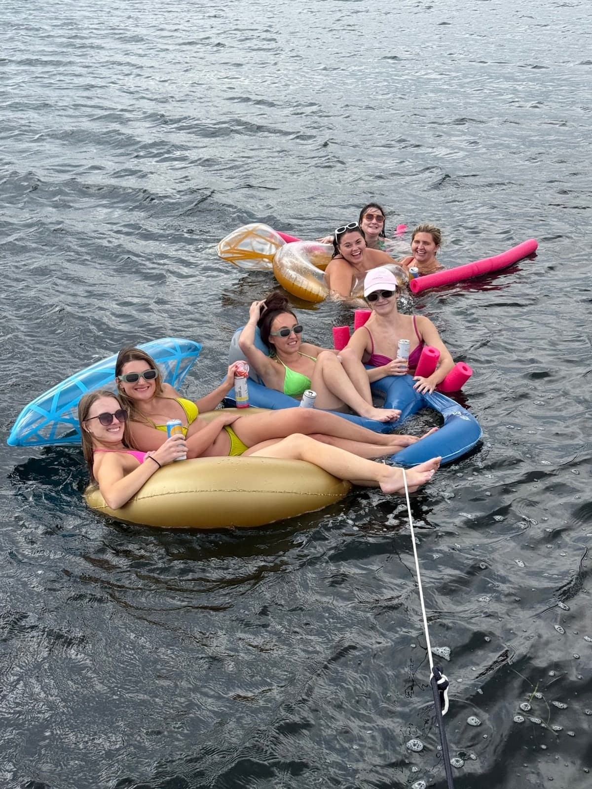 A group of friends smiling together on floats in Geneva Lake